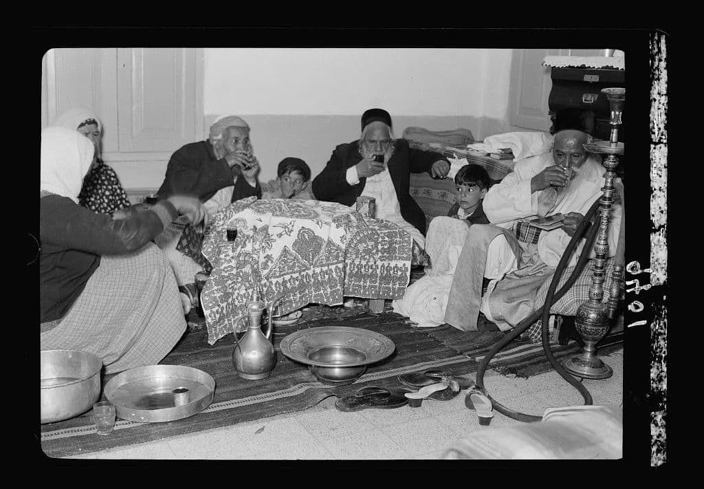 A Yemenite Jewish family drinks ceremonial wine around a covered Passover meal in 1939